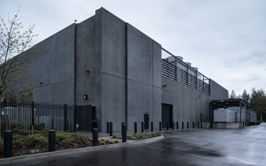 A critical facility clad in dark precast concrete panels behind security fencing